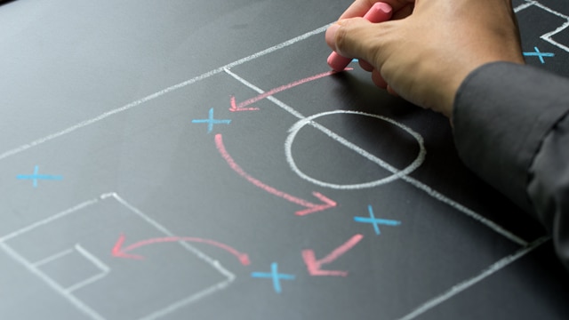 Man planning for a football strategy on blackboard