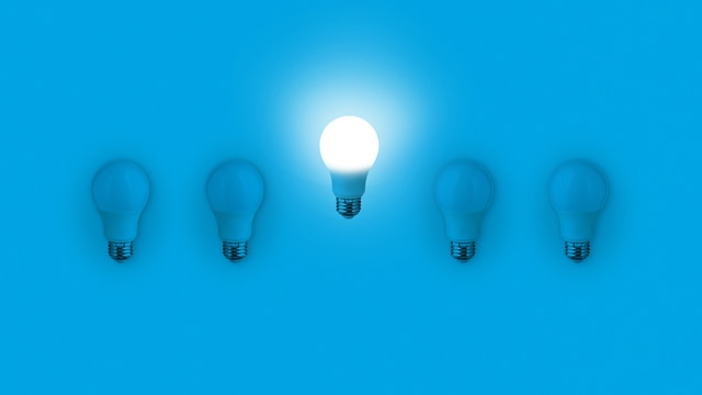Blue light bulbs with glowing one different idea on blue background. minimal concept. top view. New Creative Idea